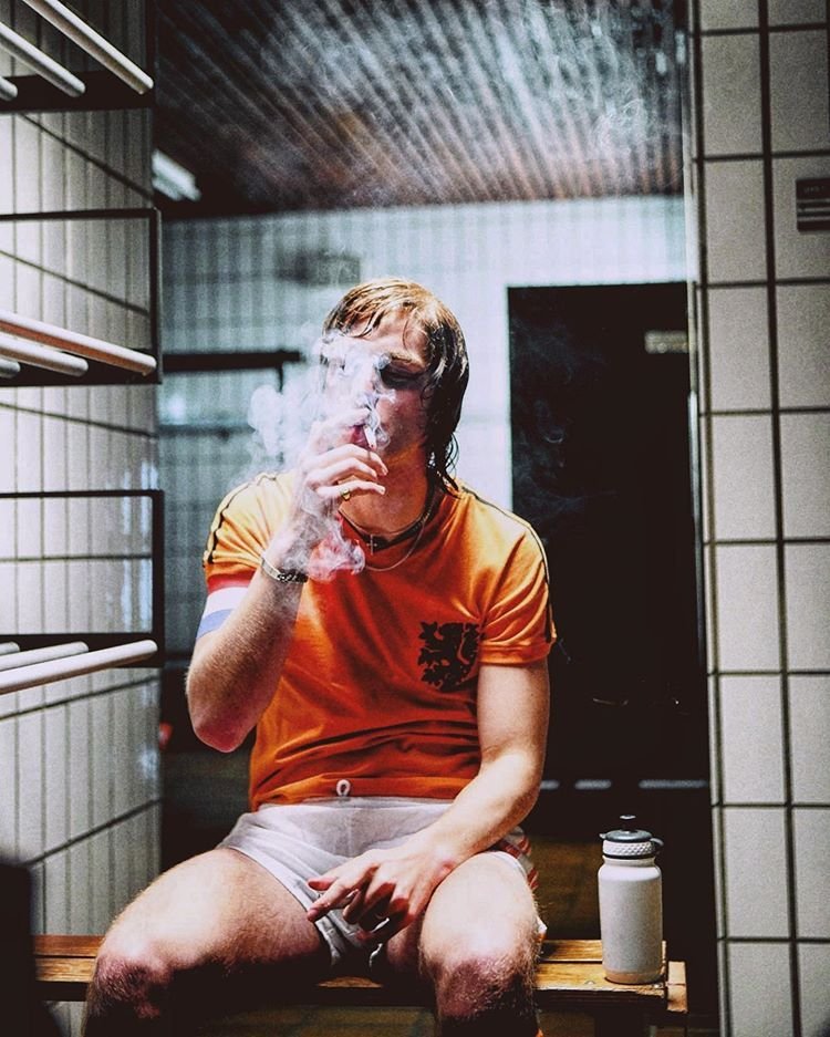 Johan Cruyff sitting in a dressing room and smoking cigarette